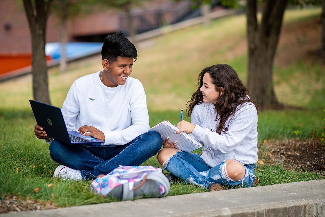 Students sitting outside studying and smiling